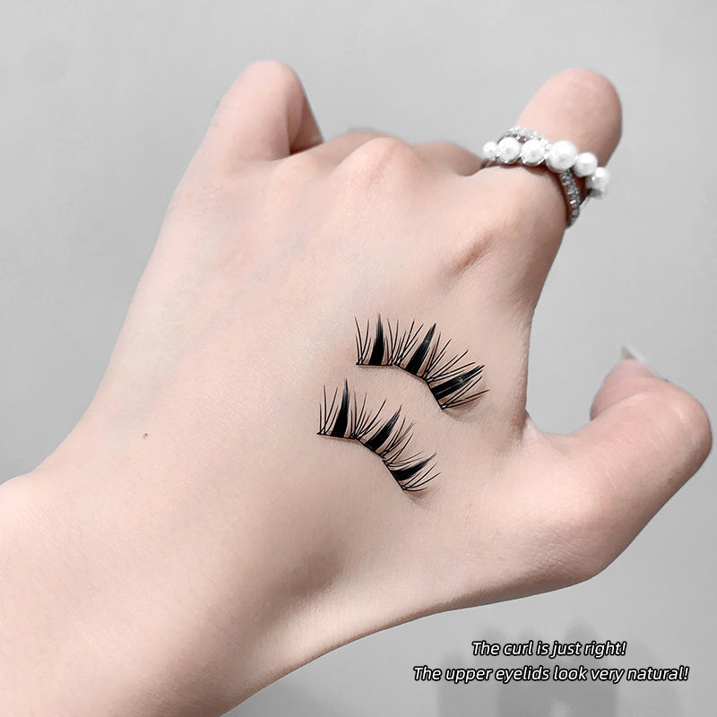 False eyelashes held between fingers with a neutral background