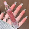 Lip gloss with 'GEGEBEAR' branding held by a hand with long, manicured nails.