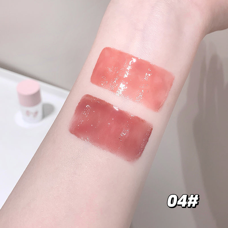 Three swatches of pink lip gloss on a person's arm with a blurred background