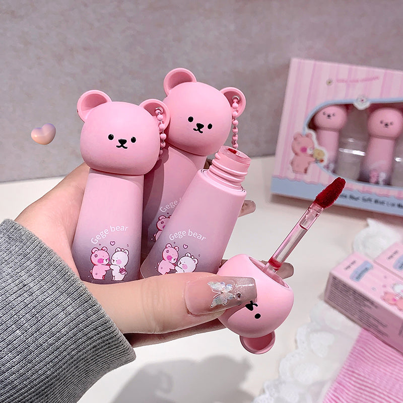 Pink bear-shaped lip glosses held by a hand with a blurred background