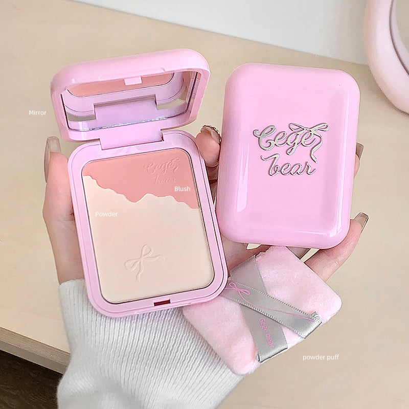 Pink makeup compact with blush and mirror, held by a hand on a light background
