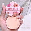 Pink drop-shaped puff with bear design held in a hand, labeled 'Geege Gear'.