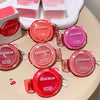 Multiple GEGBEAR lip and cheek blush creams on a beige surface with boxes in the background.