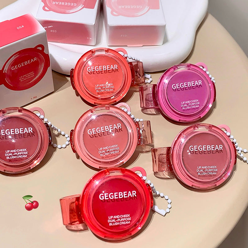 Multiple GEGBEAR lip and cheek blush creams on a beige surface with boxes in the background.