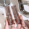 Three rose gold nail polish bottles held by a hand with a blurred background