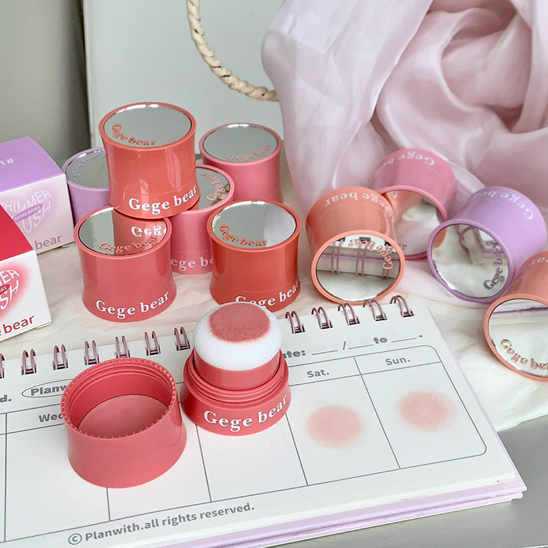 Pink and red cosmetic containers with mirrors on a planner
