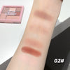 Makeup swatches on a person's arm with a makeup palette in the background