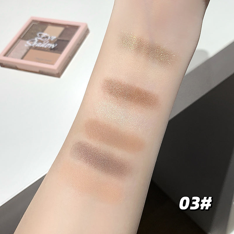 Makeup swatches on a person's arm with a palette in the background