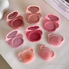 Set of pink makeup products with bear-shaped caps on a light surface.
