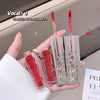 Red lip gloss with silver case held in hand against a neutral background