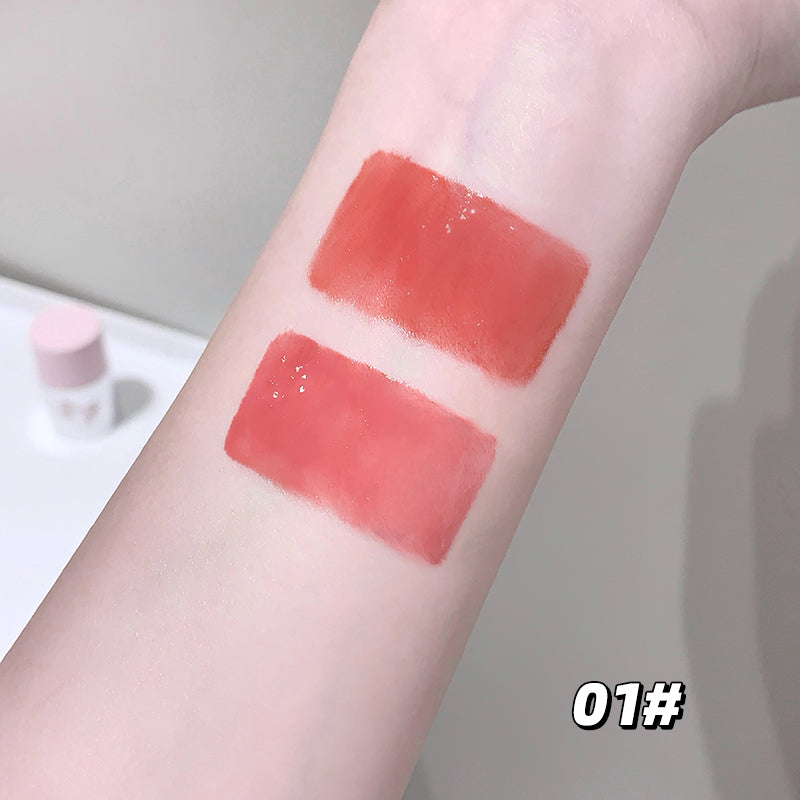 Two swatches of red lipstick on a person's arm with a neutral background