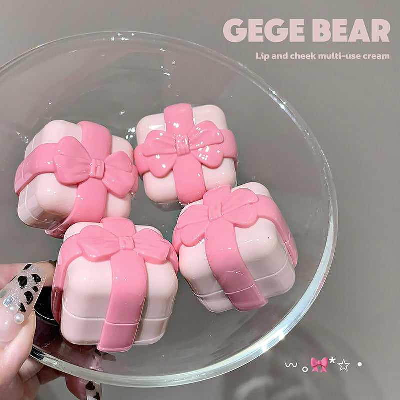 Pink lip and cheek multi-use cream containers with bows on a clear stand, branded 'GEGE BEAR'.