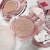 Pink makeup compact with visible powder on a light background