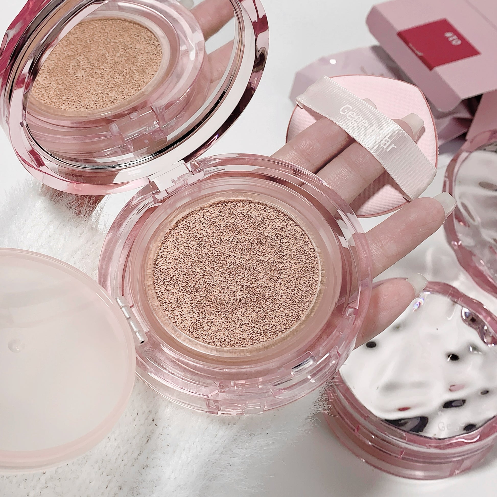 Pink makeup compact with visible powder on a light background