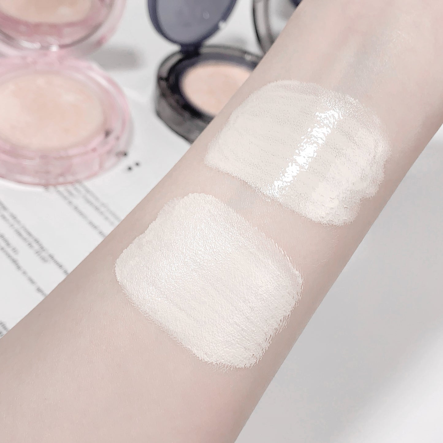 Close-up of a arm with two patches of white cream, with makeup products in the background.
