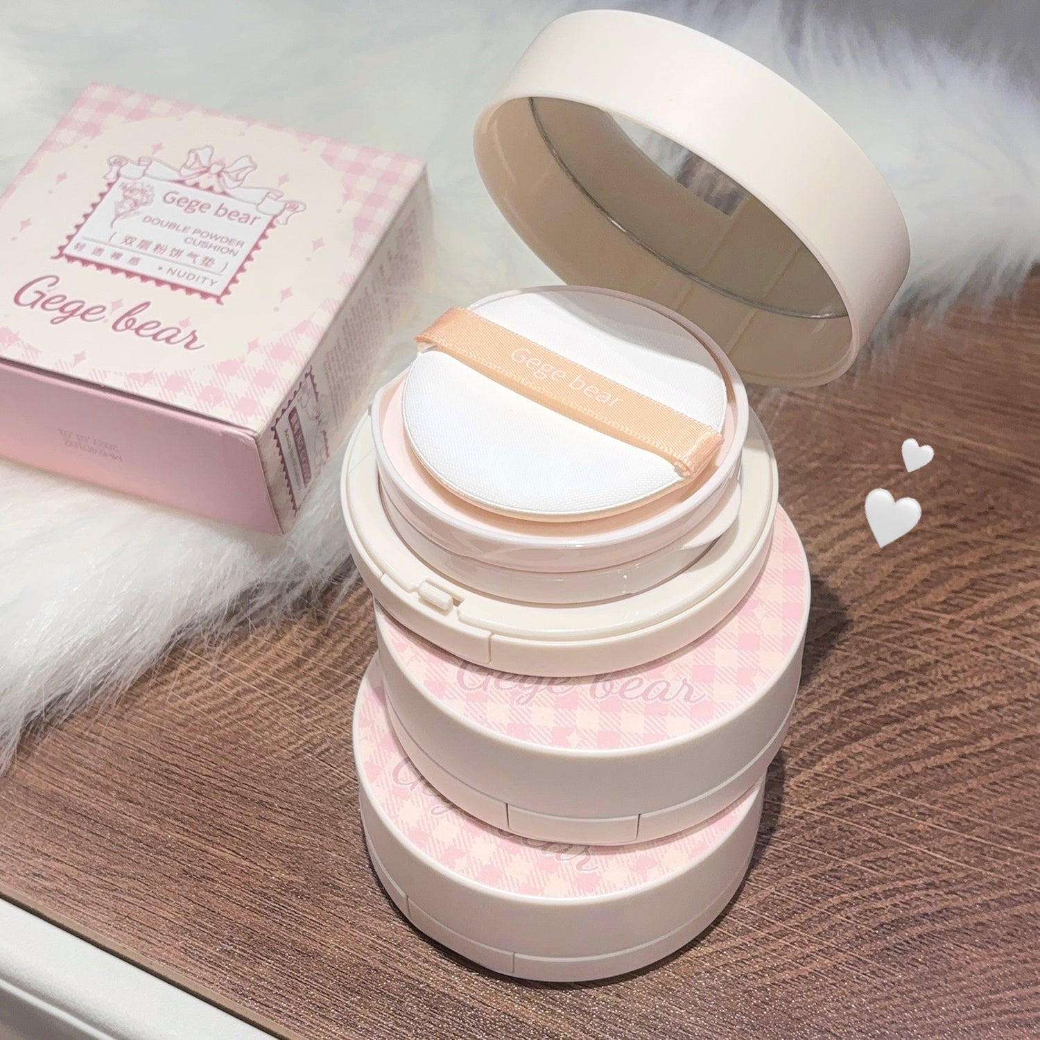 Compact powder with mirror on a wooden surface, pink box in the background