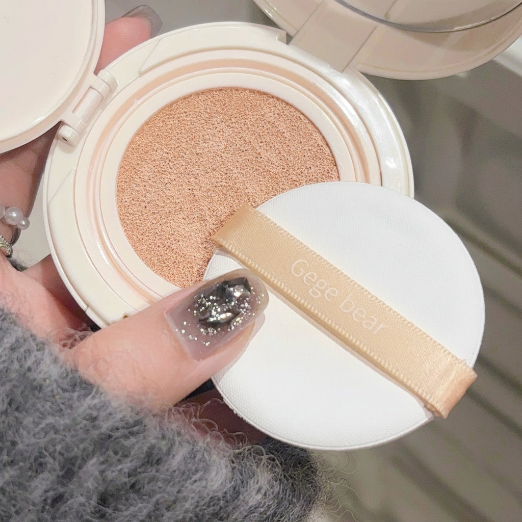 Open cosmetic compact with a puff and 'Geege Dear' branding, held by a person.