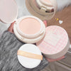 Compact powder with a mirror and pink packaging held by a person.