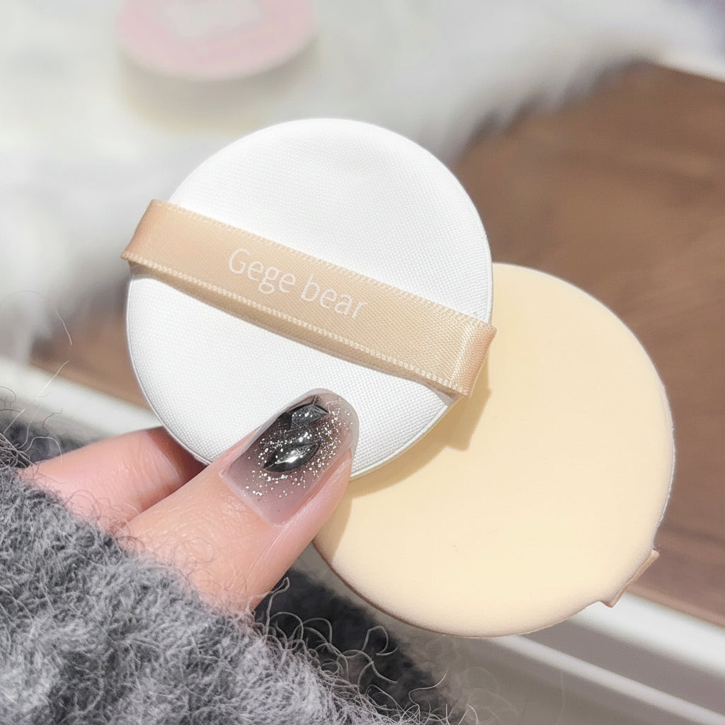 Makeup sponge with a white container labeled 'Gege bear' held by a hand.