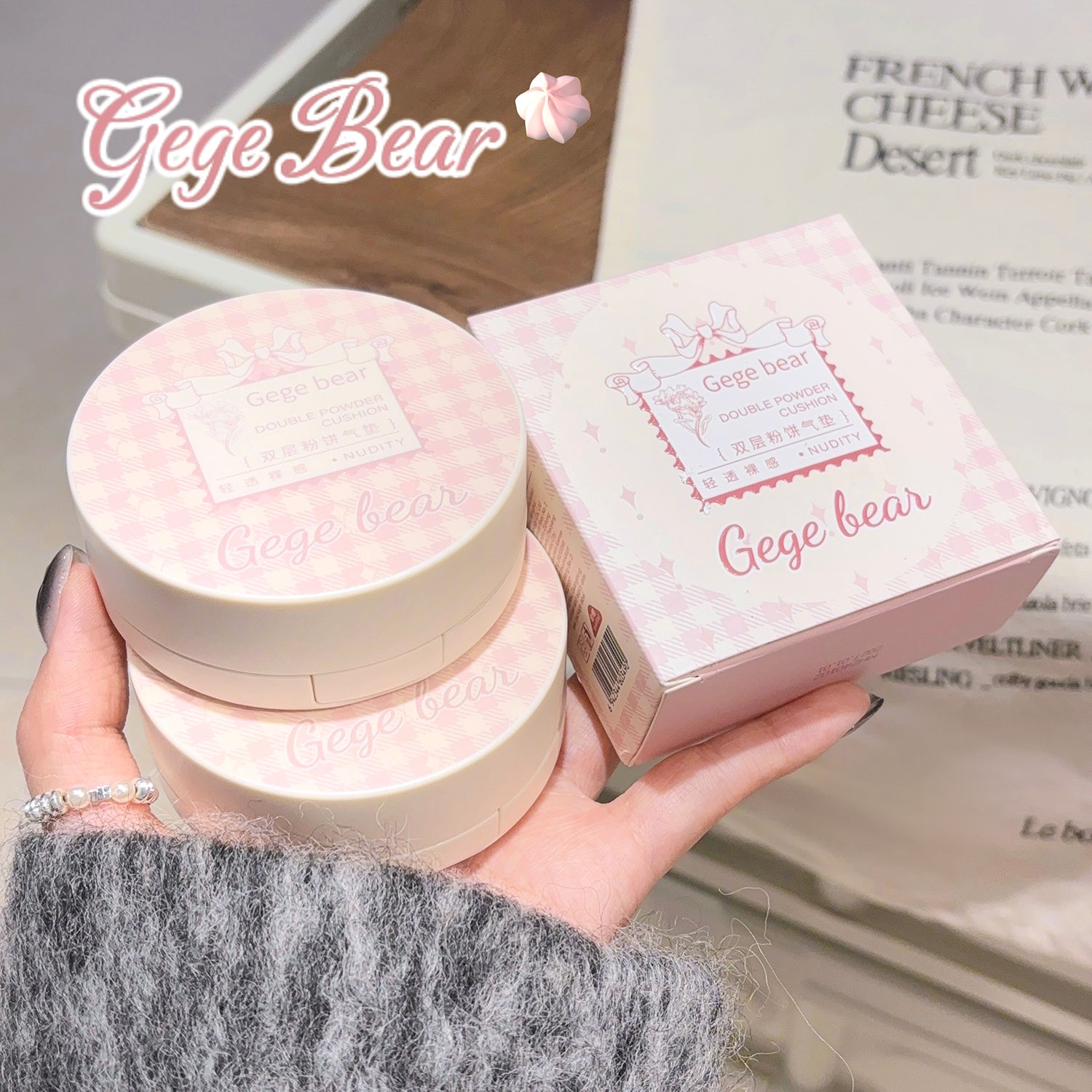 Pink cosmetic product with packaging held by a hand, branded 'Gege Bear', on a blurred background.