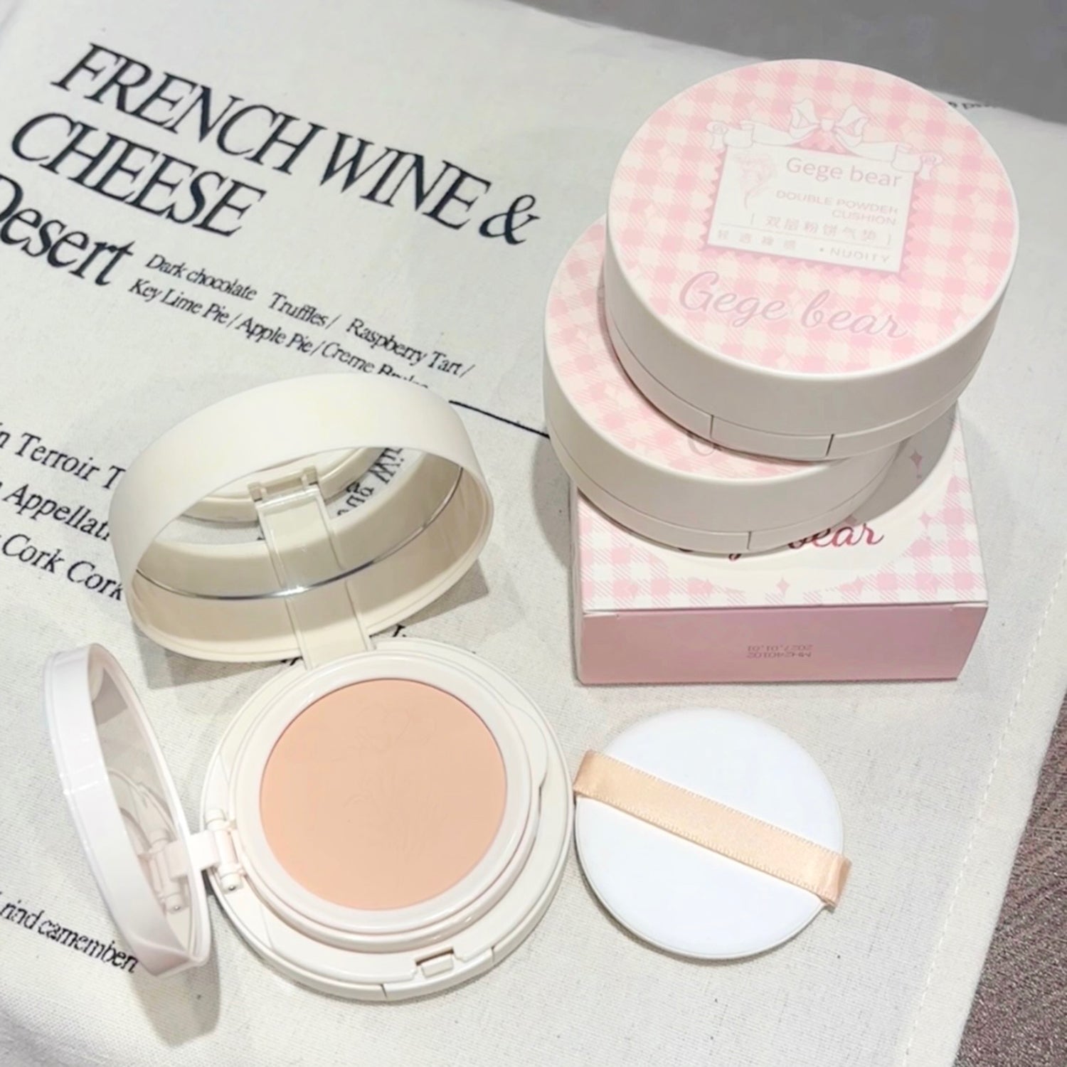 Compact powder with open lid and packaging on a surface with text in the background
