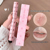 Pink lip product with packaging held by a hand, showing close-up of product on skin and lips.
