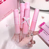 Pink lip gloss tubes held by a hand with decorative nails, against a pink and white background.