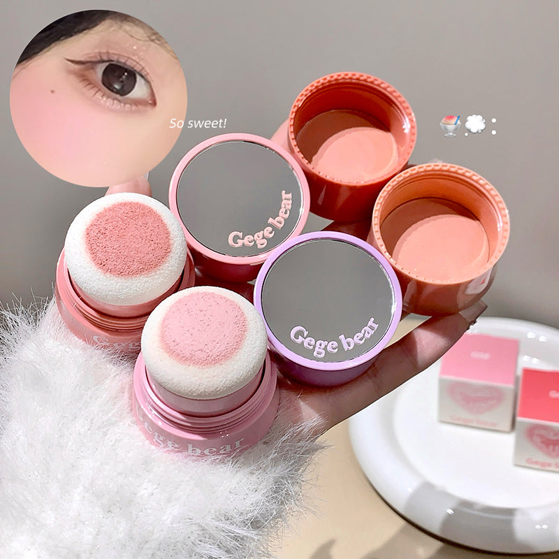 Pink makeup products with 'Geege bear' branding held by a hand.