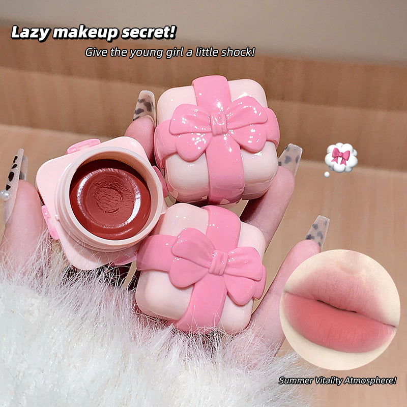 Pink makeup product with a bow design held by a hand, with text about a 'lazy makeup secret'.