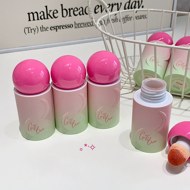 Set of pink and green lip balm containers with a brush on a white surface.