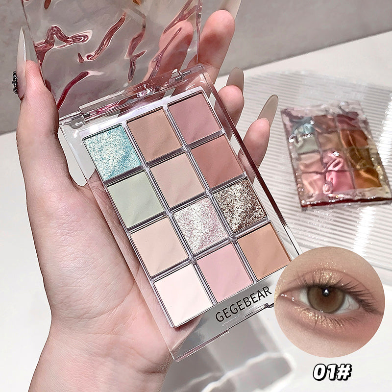 Makeup palette with 15 shades held by a hand, GEGBEAR brand visible, close-up of eye wearing makeup.