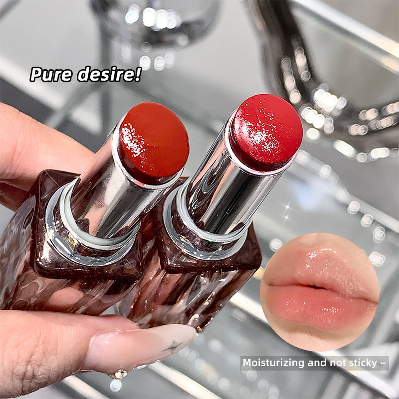 Two red lipsticks held by a hand with a blurred background