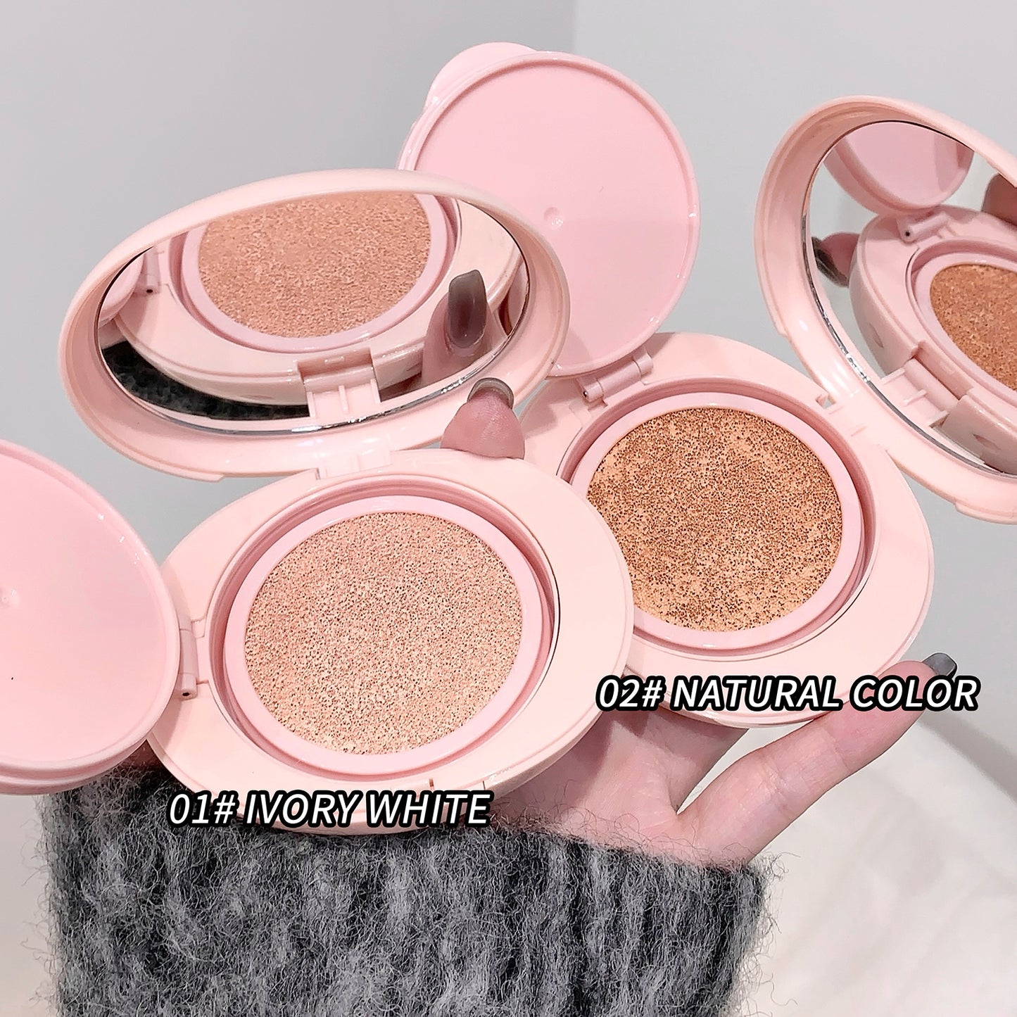 Three pink makeup compacts with different shades on a gray background