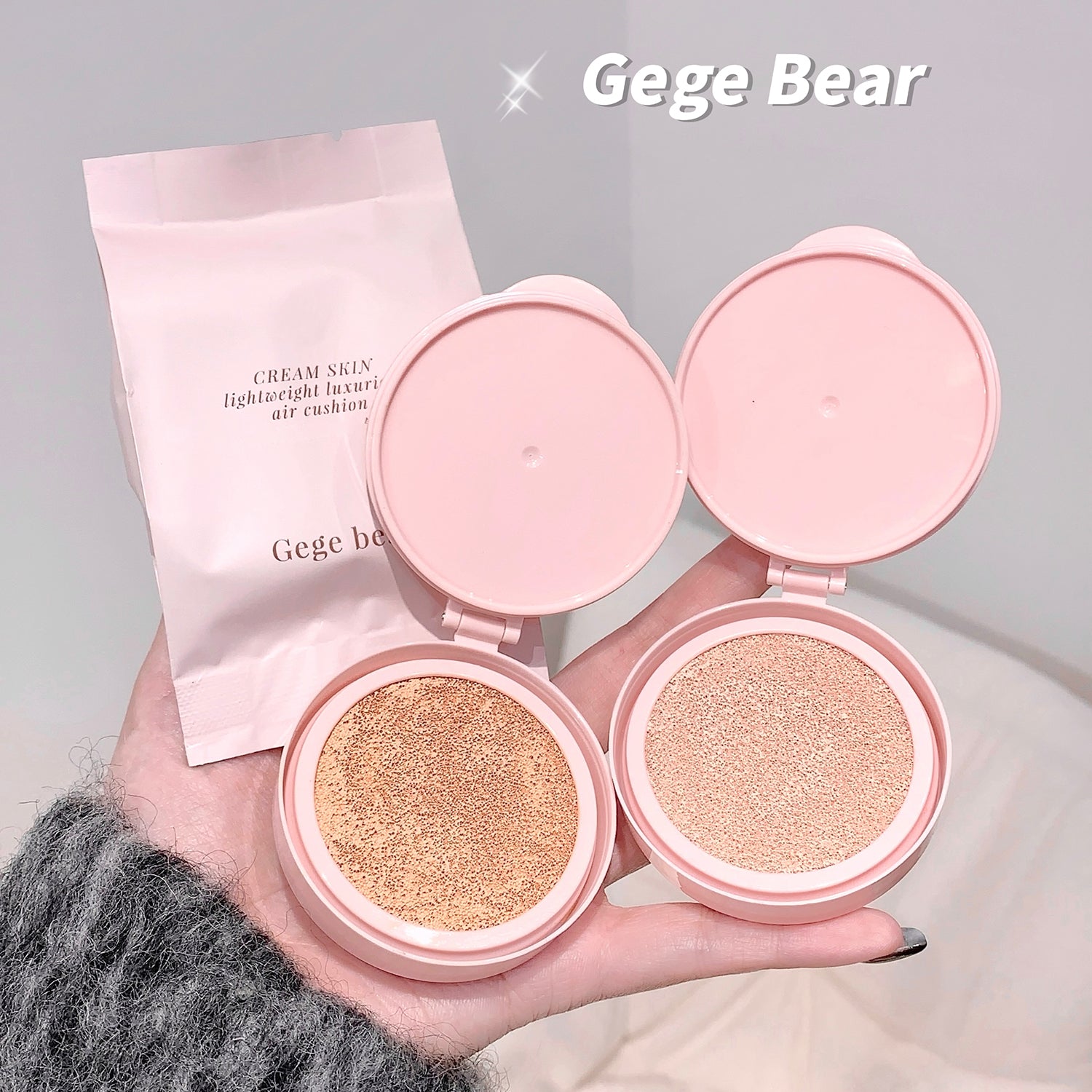 Two pink makeup cushions with open covers held by a hand, branded 'Gege Bear'.