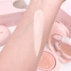 Cosmetic product swatch on skin with pink makeup items in the background