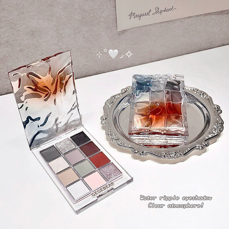 Makeup palette with water ripple design and a clear glass container on a white surface.