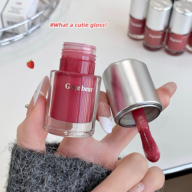 Pink nail polish bottle with silver cap being used, labeled 'Gege bear', on a white surface.