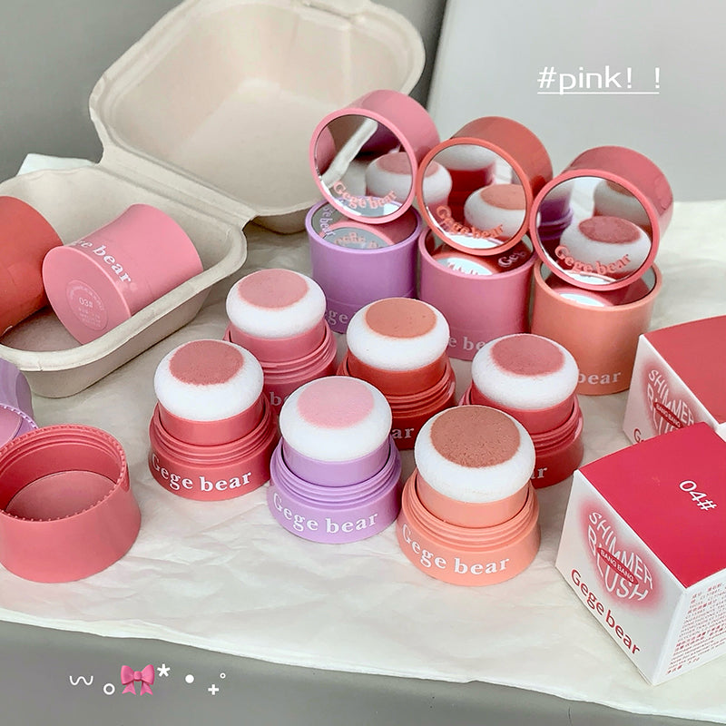 Collection of pink and purple cosmetic products with 'Gige bear' branding on a light background.
