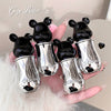 Silver bear-shaped bottle cases held in a hand with 'Gee Bear' branding.