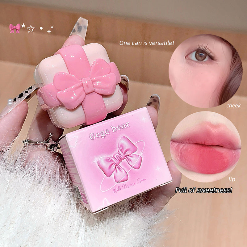 Pink cosmetic product with a bow design held by a hand, close-up of product, and a person's eye and lips.
