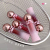 Pink lip gloss tubes with rose gold caps on a metallic surface, featuring the brand 'GEGE BEAR'.