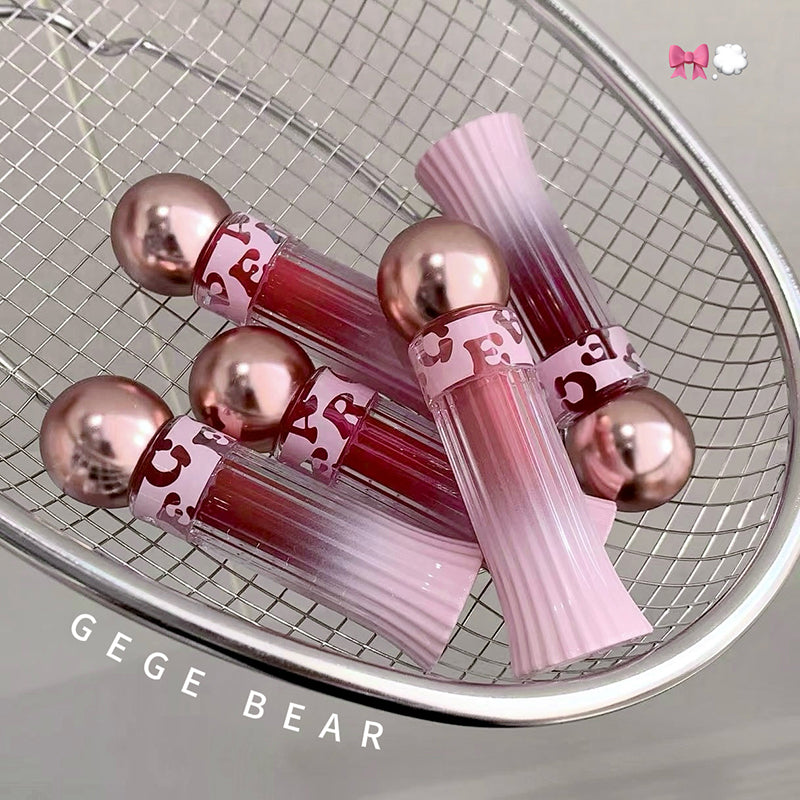 Pink lip gloss tubes with rose gold caps on a metallic surface, featuring the brand 'GEGE BEAR'.