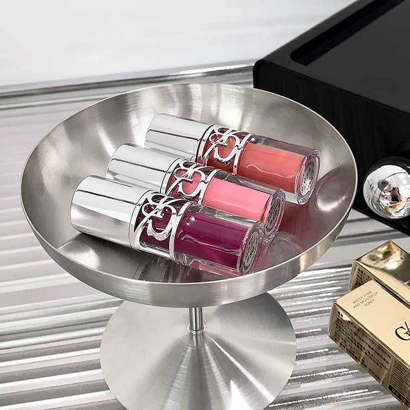 Three pink lipsticks on a metallic stand with a blurred background