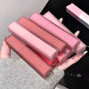 Pink lip gloss tubes with 'Gege bear' branding held in a hand against a neutral background.