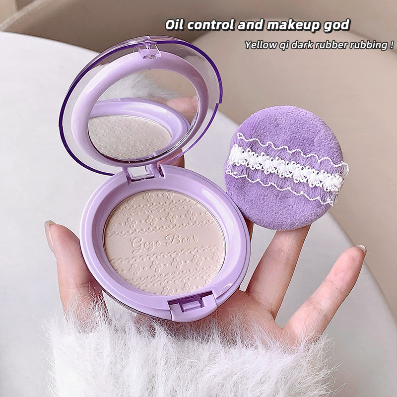Purple makeup compact and sponge held by a hand on a white background
