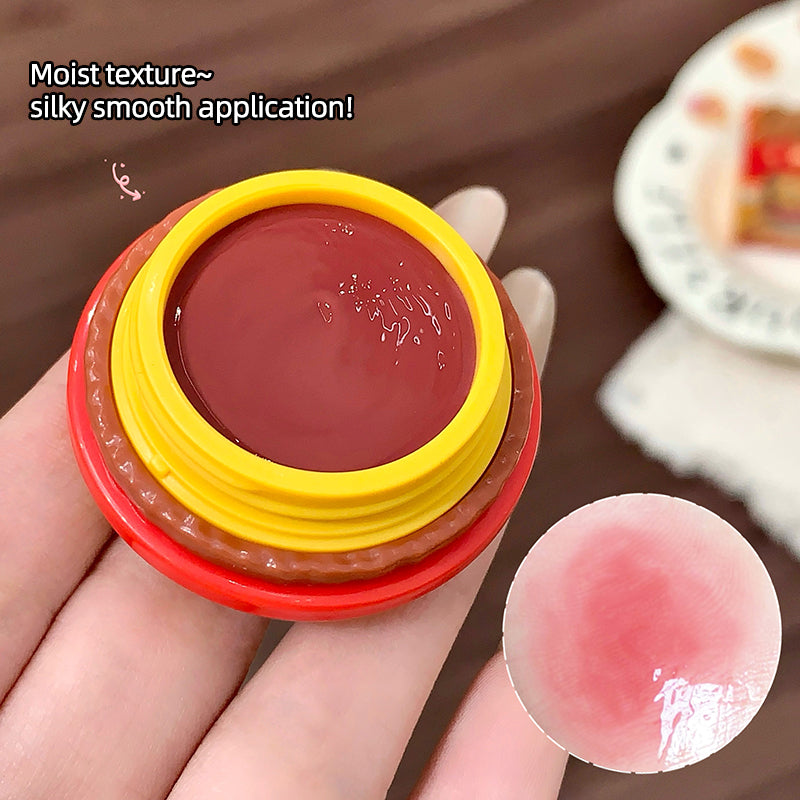 Lip balm with red and yellow casing held in a hand, close-up view.