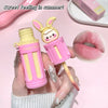 Pink and yellow lip balm with bunny design held by a hand, against a pink background.