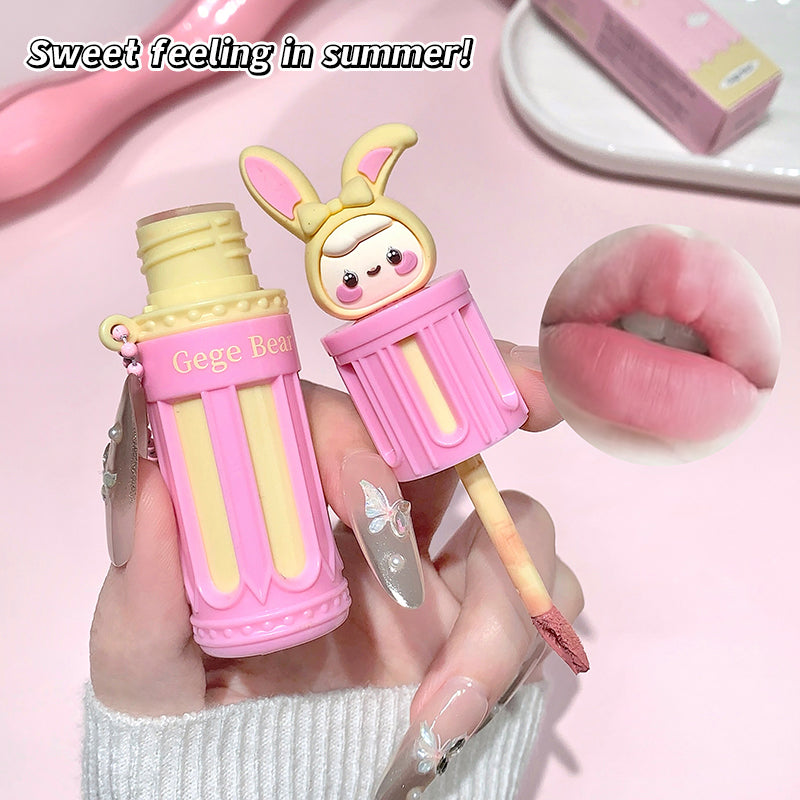 Pink and yellow lip balm with bunny design held by a hand, against a pink background.