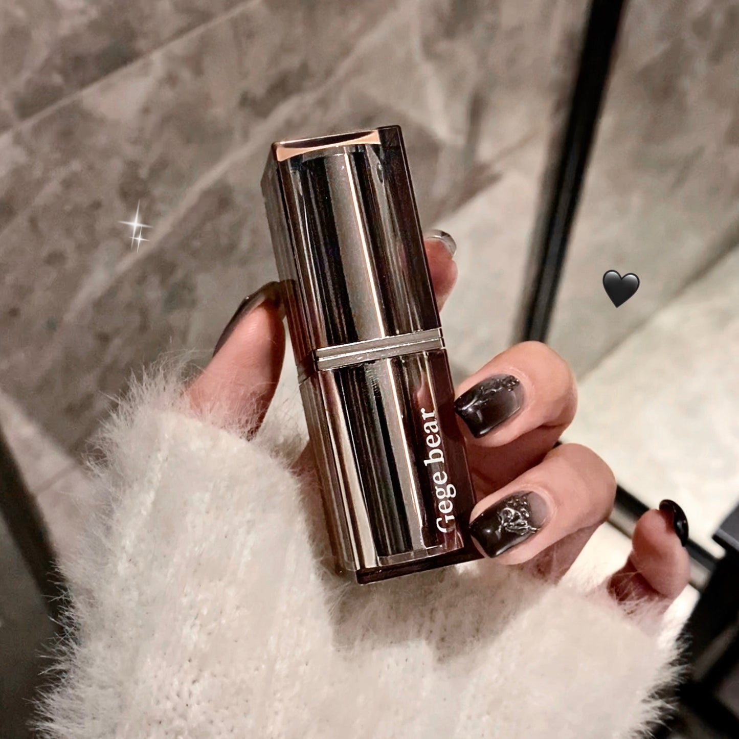 Hand holding a Gege bear lipstick with a blurred background