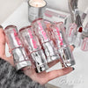 Hand holding multiple lip glosses with a blurred background